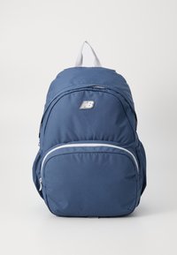 Sac à dos bleu marine avec une structure rembourrée, poche frontale zippée et accents gris. Présente un logo et une poignée de transport supérieure. Texture de tissu lisse.