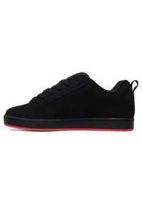 Zapatillas bajas negras de ante, con cordones planos, suela roja y un diseño minimalista con detalles cosidos y un lazo en el talón.