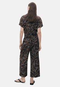 Brown patterned two-piece outfit featuring short sleeves, wide-leg pants, and floral designs in blue and cream accents. Smooth fabric texture.