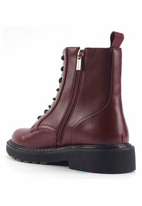 Stivaletti in pelle bordeaux con suola nera, dotati di cerniera laterale, lacci e finitura liscia. Leggero tacco e anello per indossarli facilmente.