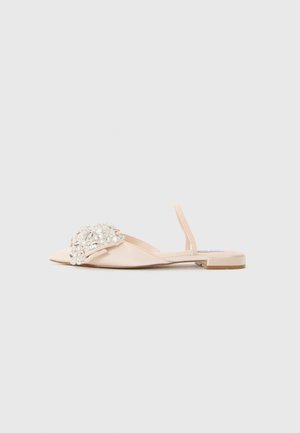 Beige flat sandal with open toe, slingback strap, and large clear rhinestone embellishments on the front strap.