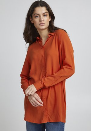 Chemise à manches longues et à boutons en tissu orange vif. Comprend un col, une texture lisse et une coupe légèrement ample. Design simple sans motifs.