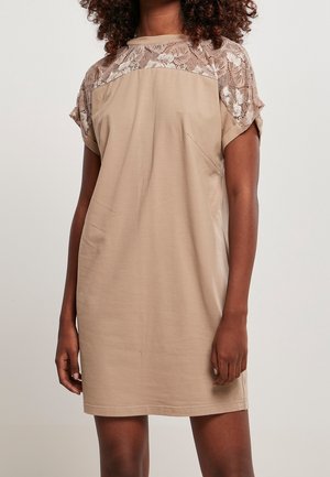 Robe beige à manches courtes, avec un motif en dentelle sur les épaules. Tissu doux, coupe décontractée, et détails de couture simples.
