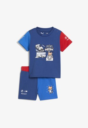 Zilā kokvilnas T-kreklu ar sarkanām piedurknēm, ar multfilmu automašīnu grafiku. Atbilstošas zilas šortus ar multfilmu varoņa druku un elastīgu jostasvietu.