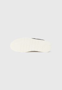 Black athletic shoe sole with a textured white rubber outsole featuring a tread pattern for traction and a logo detail.