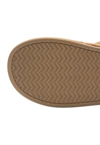 Suela de zapato de goma color tostado con un patrón en zigzag, punta redondeada y bordes cosidos, que proporciona textura y durabilidad.