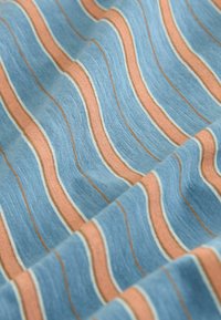 Tissu bleu avec une texture douce présentant des rayures horizontales roses, blanches et fines marron, montré en plis délicats.