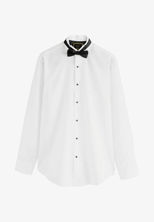 Camicia bianca a maniche lunghe con bottoni neri e papillon nero. Presenta una fodera del colletto nera e un design a orlo curvo.