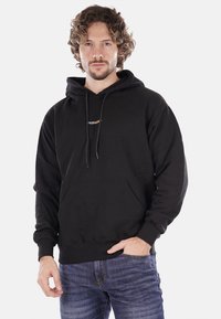 Felpa nera in cotone con tasca a marsupio, cappuccio con cordino e piccolo dettaglio testuale multicolore "PROPAGAND" sul petto.