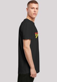 Black cotton t-shirt featuring a colorful "Super" logo in red and yellow, short sleeves, and a relaxed fit design.