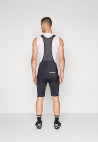 Svart sykkel-bibshorts med nettingstropper, med polstret sete og reflekterende detaljer. Glatt stoff med en tettsittende design.