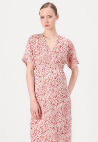 Rochie cu imprimeu floral dintr-un material moale și ușor; are mâneci scurte, decolteu în V și o talie elastică pentru o ajustare confortabilă. Culorile includ roz și alb.