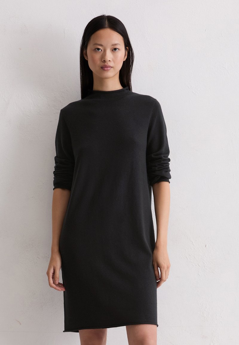 Schwarzes, langärmliges Kleid mit hohem Kragen und bequemem Schnitt aus weichem Stoff. Es verfügt über aufgerollte Ärmel und einen geraden Schnitt bis zum Saum.