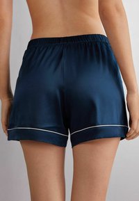 Námořnické saténové šortky s bílým lemem na spodním okraji, elastický pas, hladký povrch a uvolněný střih.