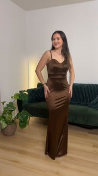 Brun satäng aftonklänning med tunna band, en figurnära överdel och en utsvängd kjol. Slät textur, strukturerad design och diskret glans.