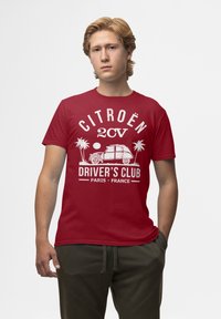 Červené bavlněné tričko s bílým textem a grafikou auta, palem a slunce, s prominencí nápisu "CITROËN 2CV DRIVER'S CLUB PARIS FRANCE".