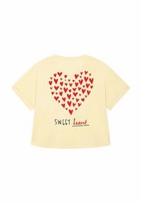 Camiseta de algodón amarilla con un gran gráfico de corazón rojo lleno de corazones más pequeños y el texto "SWEET heart" en negro debajo.