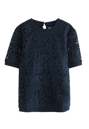 Niebieski top z krótkim rękawem z koronki w kwiatowy wzór. Okrągły dekolt i zapięcie na plecach w kształcie łezki. Gładka faktura.