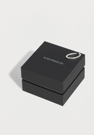Boîte à bijoux noire Alan Crocetti avec une boucle d’oreille anneau ouverte en argent reposant sur son couvercle sur fond blanc.