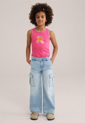 Top senza maniche rosa con grafica di frutta, abbinato a pantaloni cargo a gamba larga di un blu chiaro dotati di tasche laterali e vestibilità rilassata.