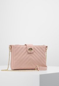 Borsa a tracolla in pelle trapuntata color rosa cipria con chiusura dorata, tracolla a catena e dettagli a motivo chevron. Forma rettangolare compatta.