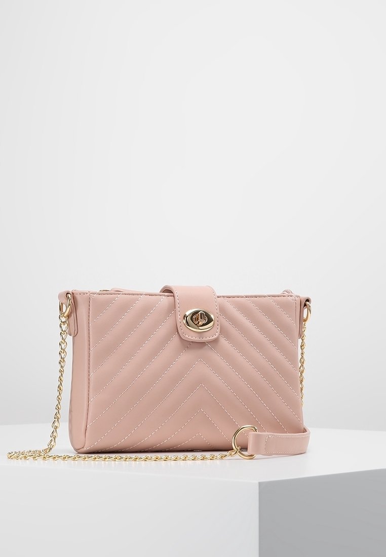 Borsa a tracolla in pelle trapuntata color rosa cipria con chiusura dorata, tracolla a catena e dettagli a motivo chevron. Forma rettangolare compatta.