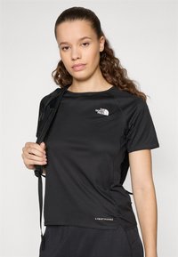 Μαύρη αθλητική μπλούζα φτιαγμένη από ύφασμα που απορροφά την υγρασία. Διαθέτει στρογγυλή λαιμόκοψη, κοντά μανίκια και υφή με σχέδιο. Λογότυπο στο στήθος.