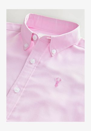 Svetloružová bavlnená košeľa na gombíky s klasickým golierom a bielymi gombíkmi. Na hrudi sa nachádza malé vyšívané svetloružové homáre.