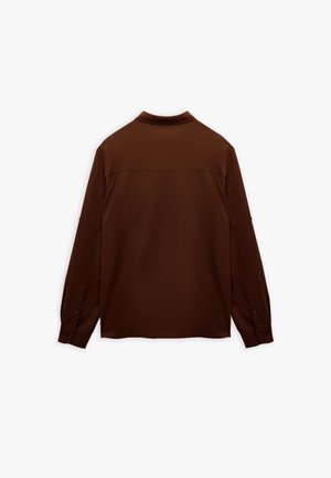Camicia marrone a maniche lunghe realizzata in un tessuto liscio. Presenta un colletto semplice, polsini abbottonati e un design minimalista senza motivi visibili.