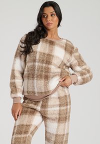 Braun und creme kariertes Fleece-Loungewear-Set. Das Oberteil hat einen runden Halsausschnitt und gerippte Bündchen; der Stoff hat eine weiche, flauschige Textur.