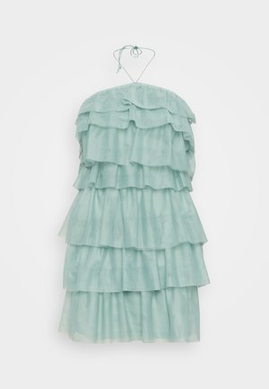 Robe superposée vert menthe avec des volants, un col halter et une silhouette fluide. Fabriquée en tissu léger et texturé.