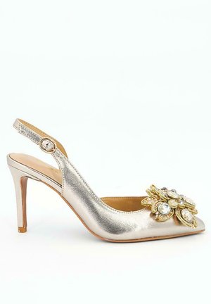 Chaussure argentée à talon haut avec bride arrière, bout pointu et ornements décoratifs en or et cristal à l'avant.