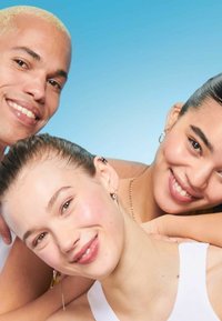 Trois visages souriants sur un fond bleu. Les individus ont des coiffures variées et portent peu d'accessoires, avec des boucles d'oreilles et des colliers visibles.