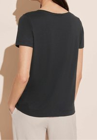 Černé tričko s krátkým rukávem a kulatým výstřihem, vyrobené z měkké látky. Obsahuje rovný střih a jemný šev na lemu.