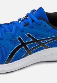 Chaussure de sport bleue en matériaux synthétiques et en maille, avec des accents noirs, une semelle texturée et des éléments de marque proéminents dans un design géométrique.
