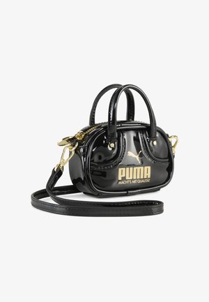 Mini bolso negro brillante con cremallera dorada, correa desmontable y logo dorado de Puma con el texto "MACHT'S MIT QUALITÄT" en el frente.