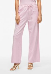Pantalons larges rose clair avec une ceinture à cordon de serrage, fabriqués en tissu doux, avec une texture lisse et une coupe droite.