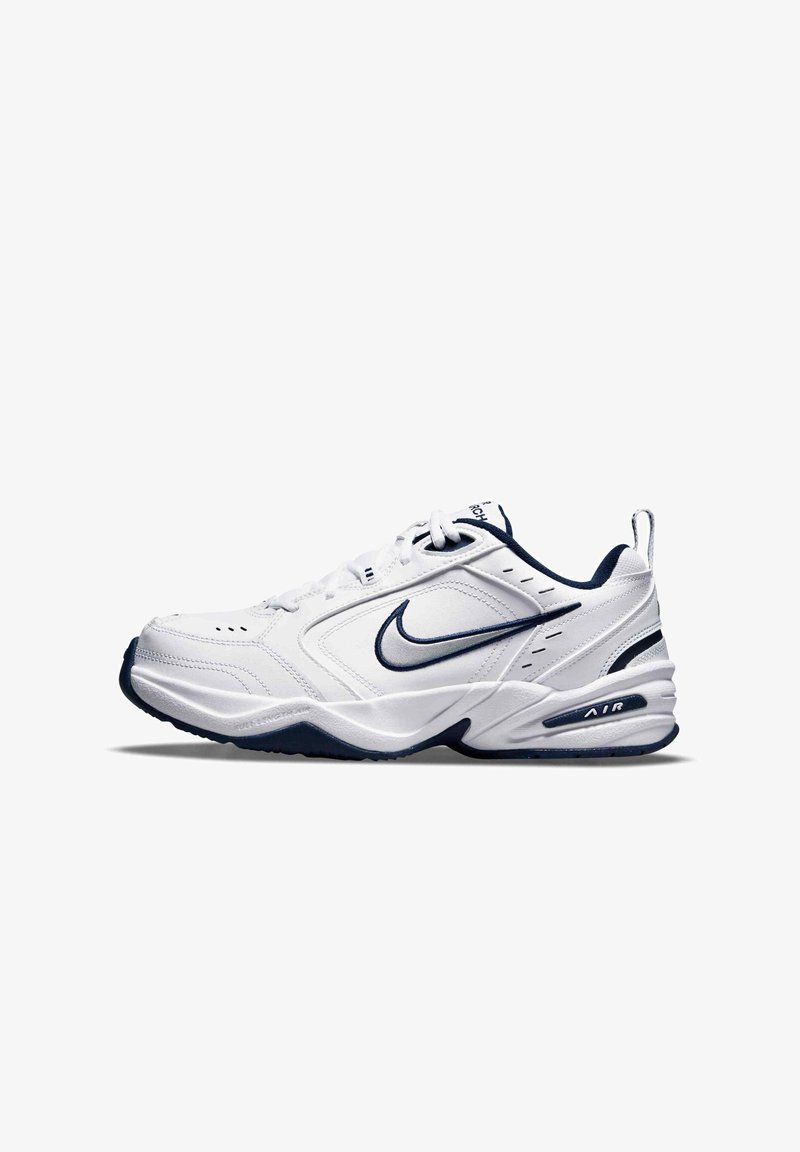 Vita sportskor med marinblå detaljer, med texturerad ovandel, snörning och synlig Air-dämpning i sulan.