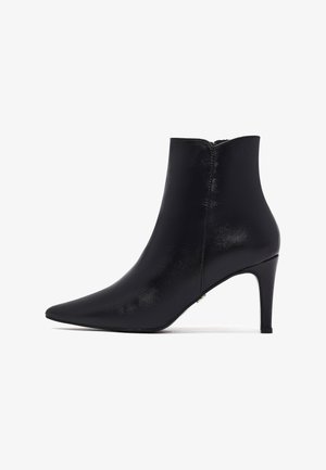 Czarny skórzany botek za kostkę z ostrym noskiem i smukłym wysokim obcasem, z bocznym zamkiem błyskawicznym, prezentowany na białym tle.