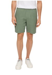 Groene textuurshorts gemaakt van lichtgewicht stof, met een elastische tailleband. Gepaarde met witte vetersneakers.