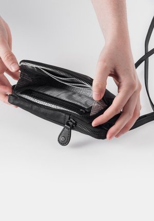 Schwarze Reißverschluss-Tasche mit einer glatten Lederoberfläche, die über zwei Fächer mit einem gittermustergewebten Innenfutter und einem abnehmbaren Tragegurt verfügt.