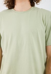 Light green cotton T-shirt with a smooth texture, crew neckline, and short sleeves. No visible patterns or embellishments.