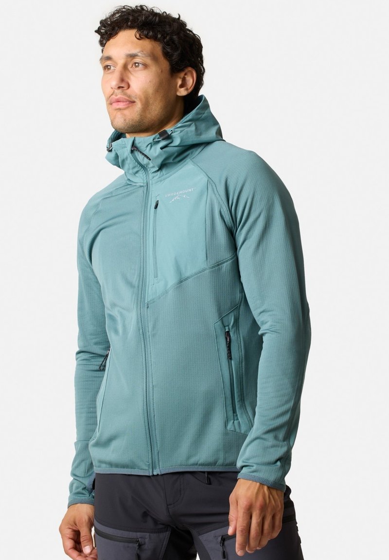 Kapuzejacke in hellem Türkis, aus strukturiertem Stoff mit Reißverschlusstaschen und taillierter Passform. Verfügt über verstellbare Bündchen und das Logo auf der Brust.