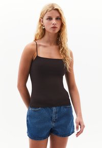Top nero a spalline sottili, dalla forma aderente e materiale morbido. Abbinato a pantaloni shorts in denim blu, dalla vestibilità rilassata, con tasche e cuciture a vista.