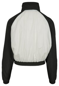 Chaqueta recortada en blanco y negro con un alto cuello, cinturilla y puños elásticos, que presenta una textura suave y un diseño de bloques de color.