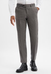 Spodnie z szarego materiału w wzór pepitki, o dopasowanym fasonie, z płaskim przodem i bocznymi kieszeniami, zestawione z czarnymi skórzanymi botkami za kostkę.