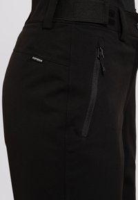 Schwarze Cargo-Hosen aus einem glatten Textil, mit einer Reißverschlusstasche, Gürtelschlaufen und einem Logo-Tag auf der Vorderseite.