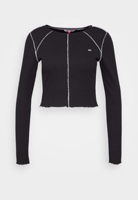Svart långärmad crop top i ribbat material, med vit sömnad längs sömmarna och en rå kant. Litet logotyp på bröstet.