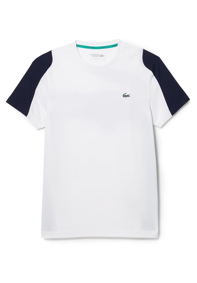 Vit sportt-shirt med mörkblå axelaccenter. Tillverkad av lättviktig tyg. Har en liten grön logotyp på bröstet.