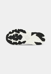 Semelle de chaussure avec un schéma de couleurs noir et blanc, en caoutchouc texturé avec plusieurs motifs de semelle pour une adhérence et un soutien.
